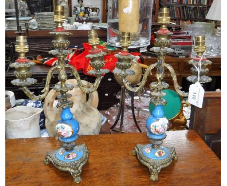 A PAIR OF CONTINENTAL BRASS CANDELABRA with blue and floral ceramic centres (drilled and converted to electricity)