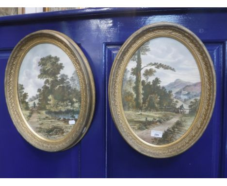 A PAIR OF 19TH CENTURY CONTINENTAL OVAL CERAMIC PLAQUES decorated with landscapes, within gilt frames, 46 cm high (overall)