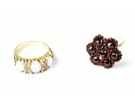 A yellow metal ladies' dress ring floral set with garnet-coloured stones, size L and a silver ring platform set with opal-eff