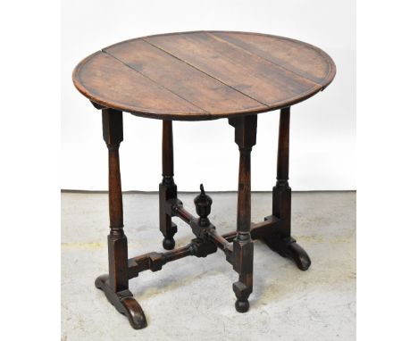 A Georgian-style oak circular folding table with dished top above folding gateleg turned and block cross-stretchered support,