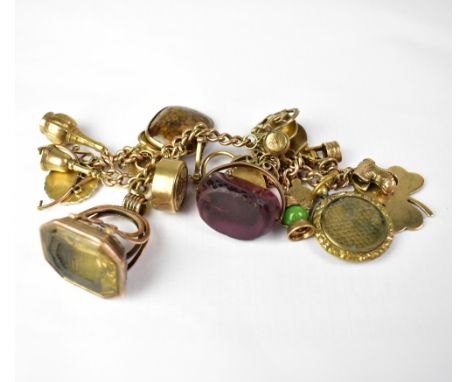 A 9ct yellow gold charm bracelet with seventeen 9ct gold charms, to include two large fobs, one in the form of a seal, smoky 