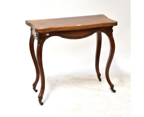 A mahogany serpentine fronted fold-over card table with circular baize lined interior above shaped frieze, raised on carved s