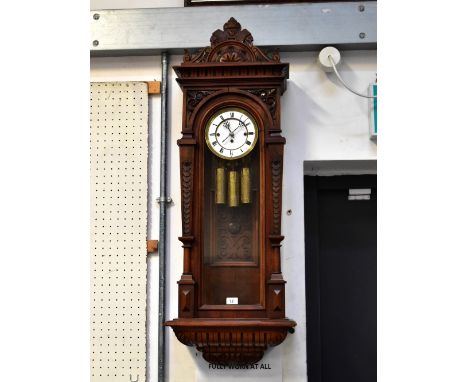 An early 20th century walnut cased triple weight Vienna wall clock, the carved arched pediment above moulded cornice and arch