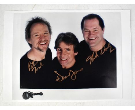 THE MONKEES; a colour photograph bearing the signatures of Peter Tork, Davy Jones and Mickey Dolenz, 20 x 25cm.We have not au