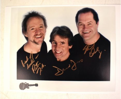 THE MONKEES; a colour photograph bearing the signatures of Peter Tork, Davy Jones and Mickey Dolenz, 20 x 25cm.We have not au