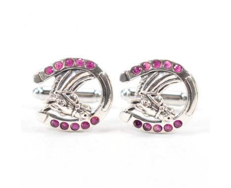 A pair of silver and ruby equestrian cufflinks. The heads in the form of horses in horse shoes set with round cut rubies. Mar