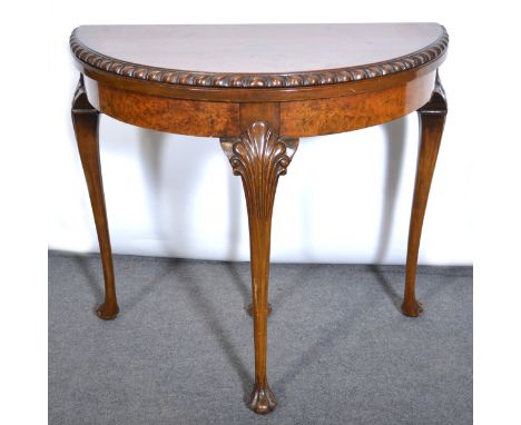 A walnut veneer demi-lune card table, the top with a gadrooned edge, plain frieze, carved cabriole legs, width 84cm, depth 42