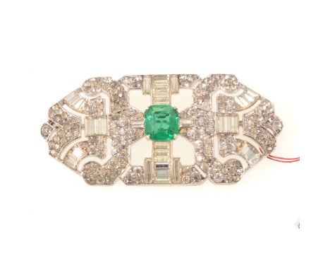 An Art Deco faux emerald and clasr paste brooch, the green step cut faux emerald with simulated inclusions,10x9mm, four claw 