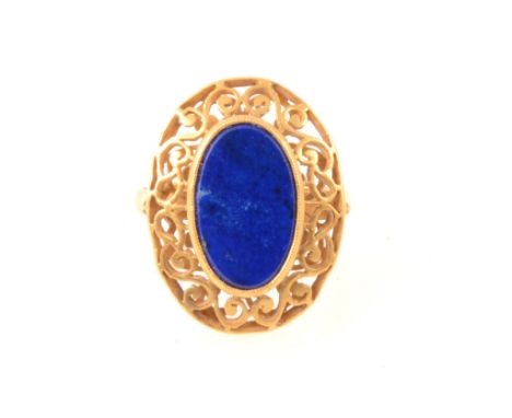 An 18 carat yellow gold dress ring set with a slice of lapis lazuli, 13x8mm, pierced scroll work surround to head 23x17mm, Lo