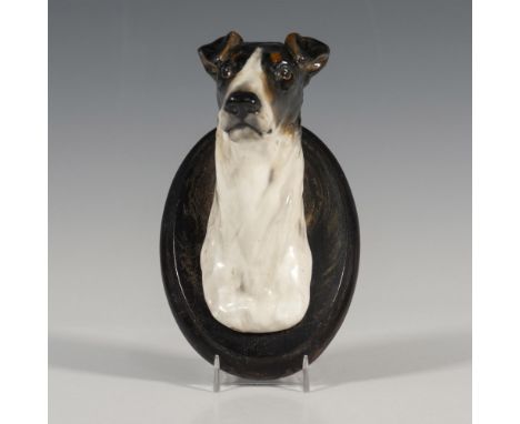 Smooth Haired Fox Terrier. A white and dark brown glazed figure of a dogs head mounted to an oval wooden panel. Issued: 1930s
