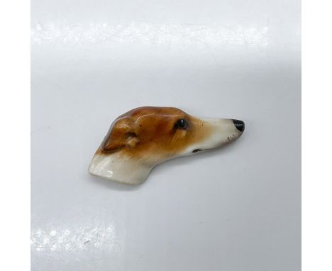 Pottery pin molded as a Greyhound head; needle pin fasten. Light brown and white coloration. Royal Doulton impressed stamp. I