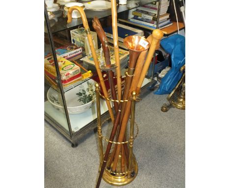 A BRASS STICK STAND CONTAINING WALKING STICKS, FENCING SWORDS, ETC