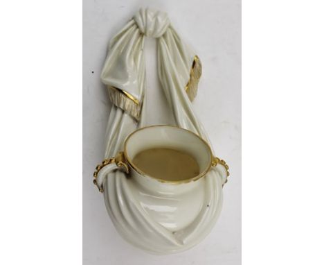 A ROYAL WORCESTER PORCELAIN WALL POCKET, modelled as a Classical Amphora, suspended by a fringed scarf, gilded ivory ground, 