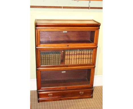 A GLOBE-WERNICKE BRANDED THREE TIER MAHOGANY GLASS FRONT BOOKCASE the plinth section having single full width drawer, 120cm x