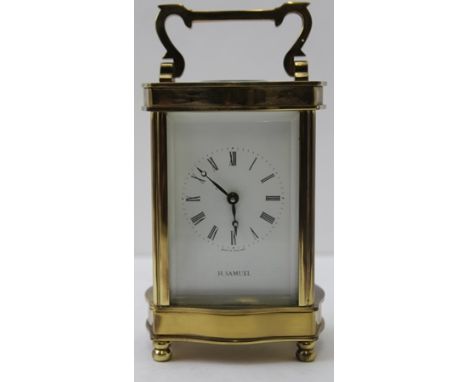 A 20TH CENTURY CARRIAGE CLOCK, brass serpentine frame, white enamel dial with Roman numerals, inscribed 'H Samuel', 12cm high