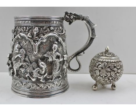 A FAR EASTERN WHITE METAL TANKARD, cast, chased and repousse decorated in the round with dancers in landscape, beneath arbour