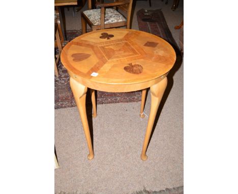 A circular inlaid card table, the top inlaid with playing card symbols, raised on slender cabriole legs.