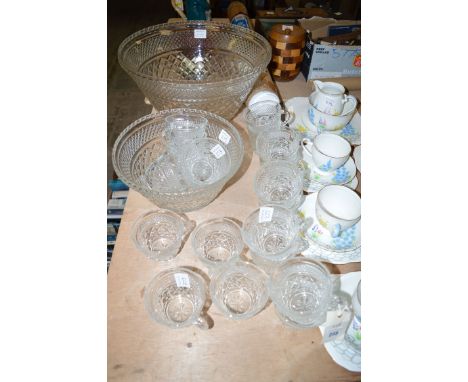 A large pressed glass punch bowl; together with a smaller one and nineteen moulded glass tea cups. (21)