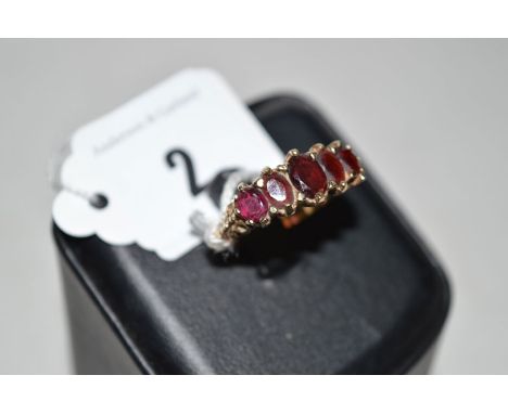 A garnet ring, the five graduated oval facet cut garnets claw set above scrolling shoulders on 9ct. yellow gold shank, ring s