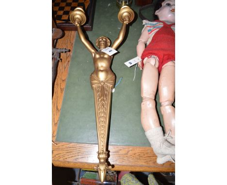 A gilt metal wall light in the form of a female nude holding two candlesticks.