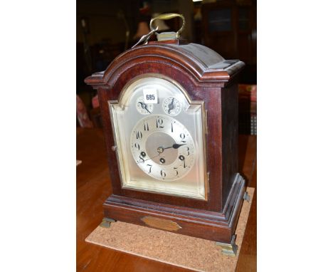 A mahogany cased bracket clock, fitted Junghans movement to an arabic dial with subsidiary dials, the arched case with brass 