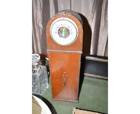 An aneroid barometer in an oak case with cupboard door below.