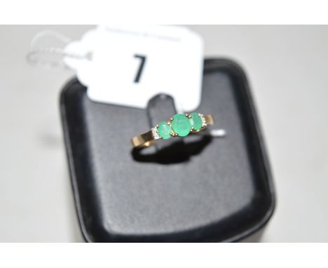 An emerald and diamond ring, the three graduated oval facet cut emeralds each four claw set, with two diamonds to each should