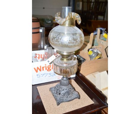 A Victorian table oil lamp with glass reservoir and cast metal base, and an opaque shade; together with a box of glass chimne