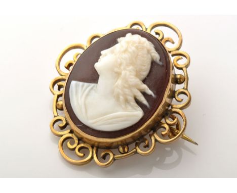 A carved shell cameo brooch, the oval central cameo depicting a classical bust portrait within yellow metal scroll frame, bro