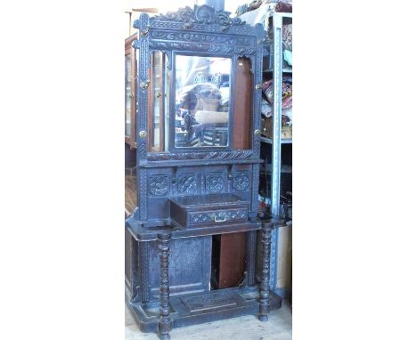 A Victorian carved oak hallstand, with central rectangular mirror, surrounded by hooks with scrolling leaf carving, having a 