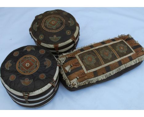 A pair of circular leather pouffes, together with a rectangular pouffe, all with stitched and tasselled decoration, diameter 