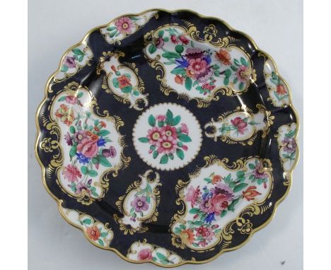 An 19th century Worcester porcelain plate, with scale blue ground and reserves decorated with flowers, having a shaped edge, 