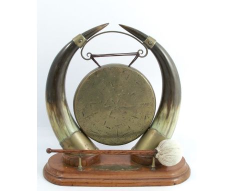 A 19th century table gong, the brass gong supported on a pair of horns, on an oak plinth with hammer, height 14insCondition R