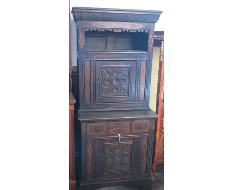 An Antique oak cabinet, the upper section fitted with a shelf over a cupboard, the base fitted with drawers and a cupboard, t