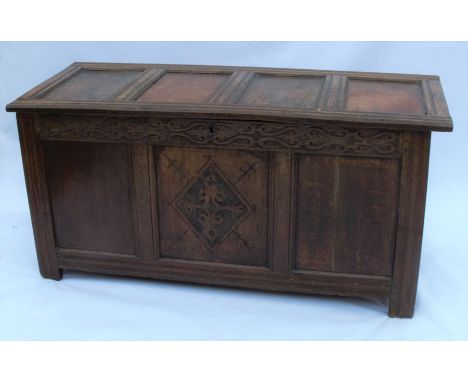 An Antique oak coffer, having a four-panelled lid, the front with carved frieze over three panels with carving to central pan