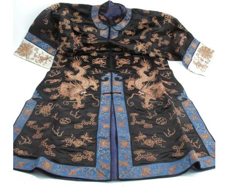 A Chinese silk embroidered coat, decorated in gold with dragons and various repeating symbols, with blue border and white to 