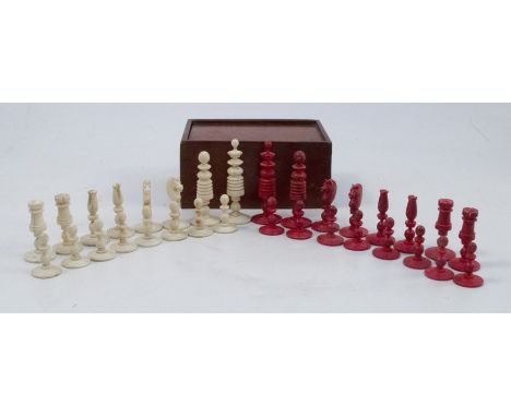 An Antique carved bone chess set, stained red and natural, thirty-two pieces, height of king 2.75ins, in a mahogany box with 