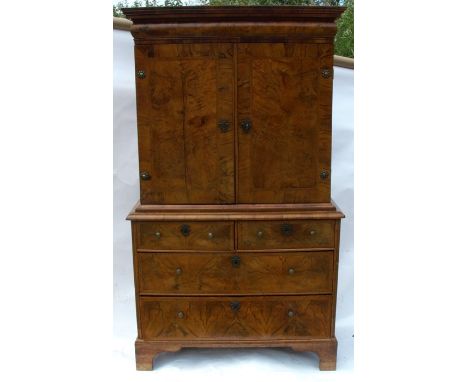 An Antique walnut cabinet on chest, the upper section fitted with a frieze drawer over a pair of cupboard doors opening to re