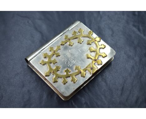A white metal cigarette case of hinged rectangular book form, having applied brass decoration with 'K 1958 2008' engraved, 9.