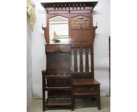 A Liberty's style Arts & Crafts walnut hall stand having a moulded cornice over a mirror, an embossed copper panel, hooks, a 