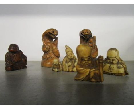 A Japanese carved fruitwood netsuke of a seated figure, three early 20th century carved ivory netsukes and two fruit wood car