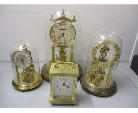 Four reproduction clocks to include three anniversary clocks with glass domes and a carriage clock with a quartz movement, a 