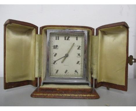 An Art Deco chrome plated bedside, 8 day alarm clock in a fitted Harrods leather case, 3 1/4" h x 3 1/4" w, excluding case 