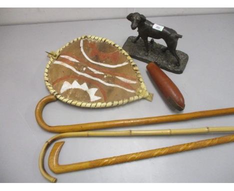 A cast iron model of a dog on a plinth, three walking sticks and an Aborigine shield and a flask 