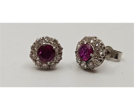 A pair of 9ct. white gold, ruby and diamond cluster stud earrings, set round cut ruby to centre, bordered by round cut diamon