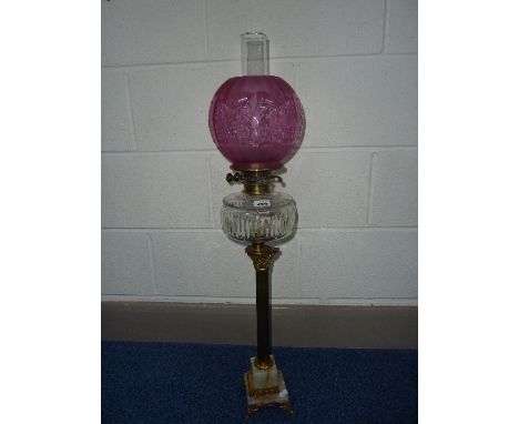 A BRASS OIL LAMP, with cut glass well and cranberry coloured shade, height (top of shade) 77.5cm approximately, (restored)