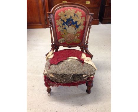 A Victorian nursing chair with tapestry panelled back, reeded side columns, low arms, reeded and turned front legs and china 