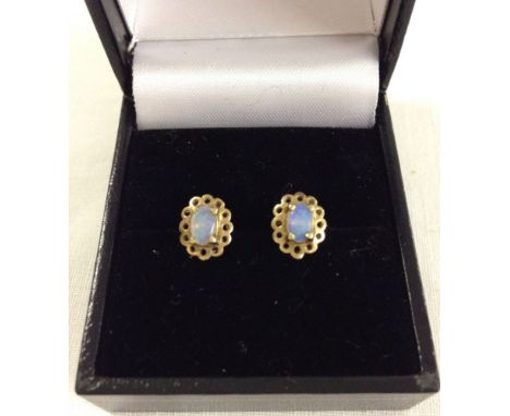 A pair of gold stud earrings set with oval opal stones.