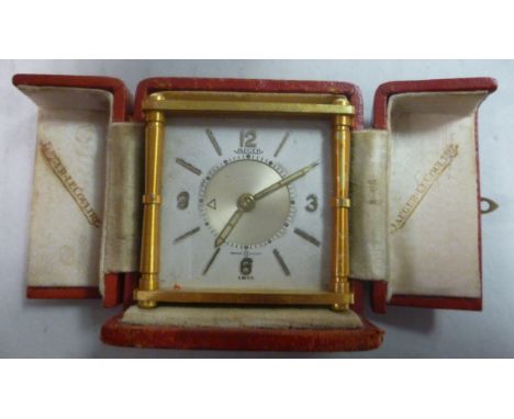 A Jaeger-LeCoultre lacquered brass, box cased traveller's timepiece with opaque glass panelled sides and pillared corners; th