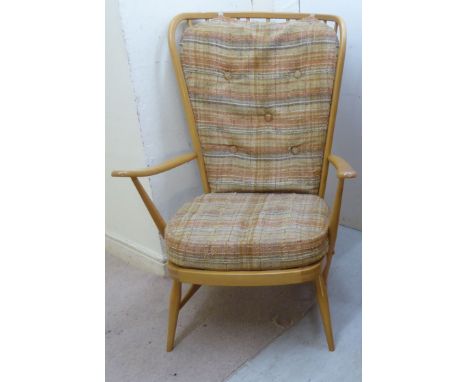 An Ercol pale coloured beech framed Windsor style, high, round, spindled back, open arm chair, the strapworked seat with stri